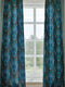A sheer curtain panel featuring a repeating pattern of stylized owls in luminous blue tones, surrounded by delicate botanical flowers and flourishes on a dark background.